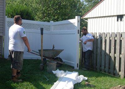 men installing white vinyl fence