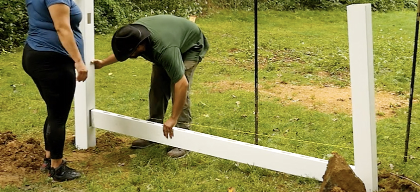 couple installing white vinyl fence